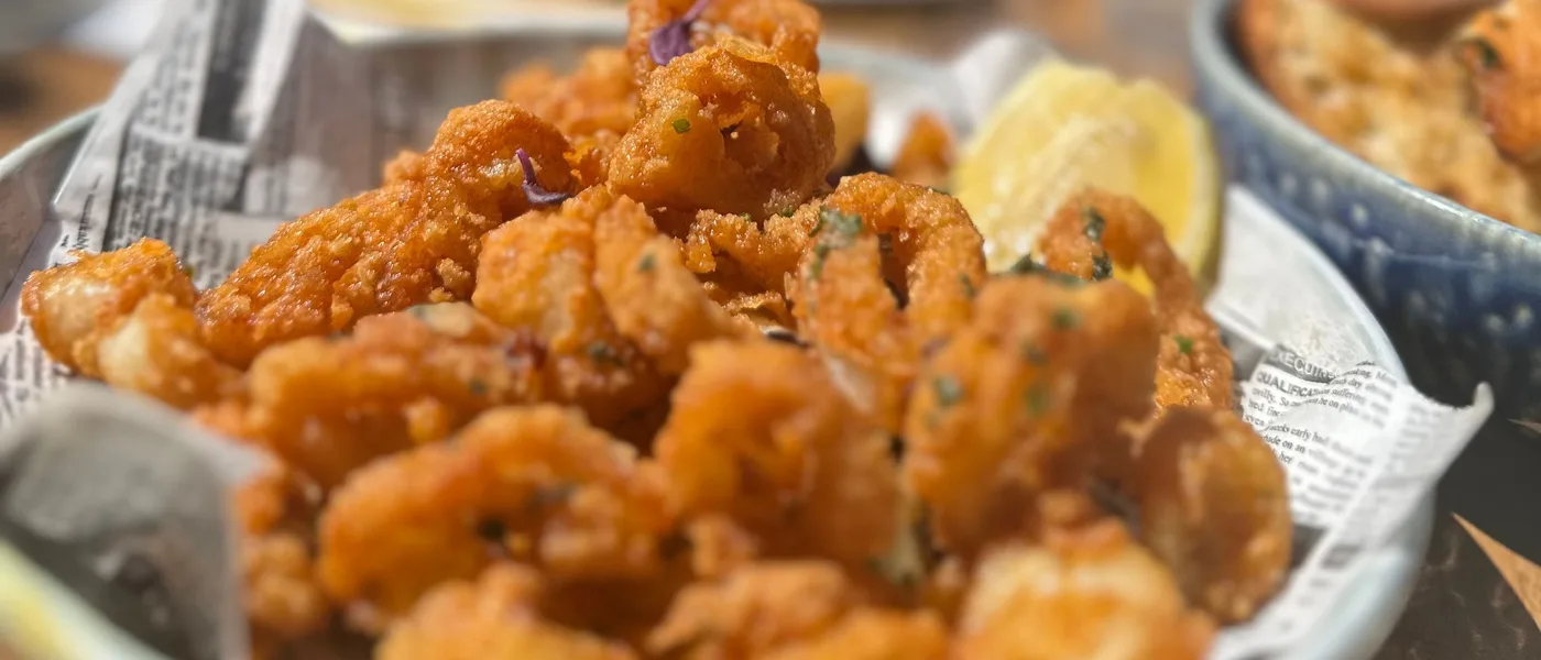 Schaal krokant gefrituurde calamari op krantenpapier, met een partje citroen