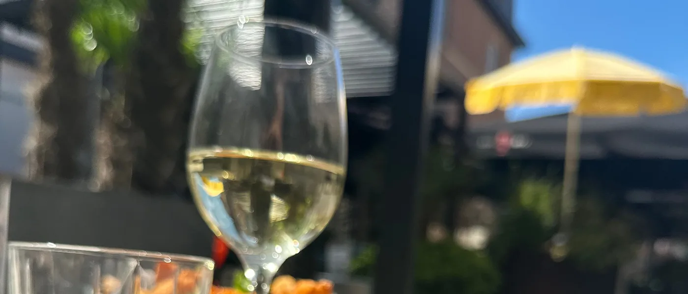 Glas witte wijn op het terras aan de Vlasmarkt, in de zon